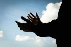 A person holding their hands out in front of a blue sky