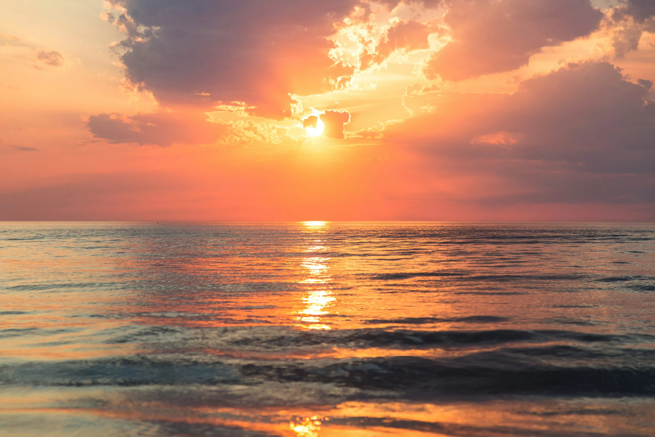 Sun breaking through clouds over a calm sea