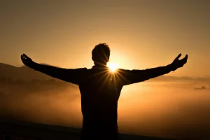 Silhouette photo of man on cliff during sunset