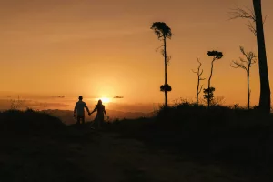 A man and a woman holding hands as the sun sets
