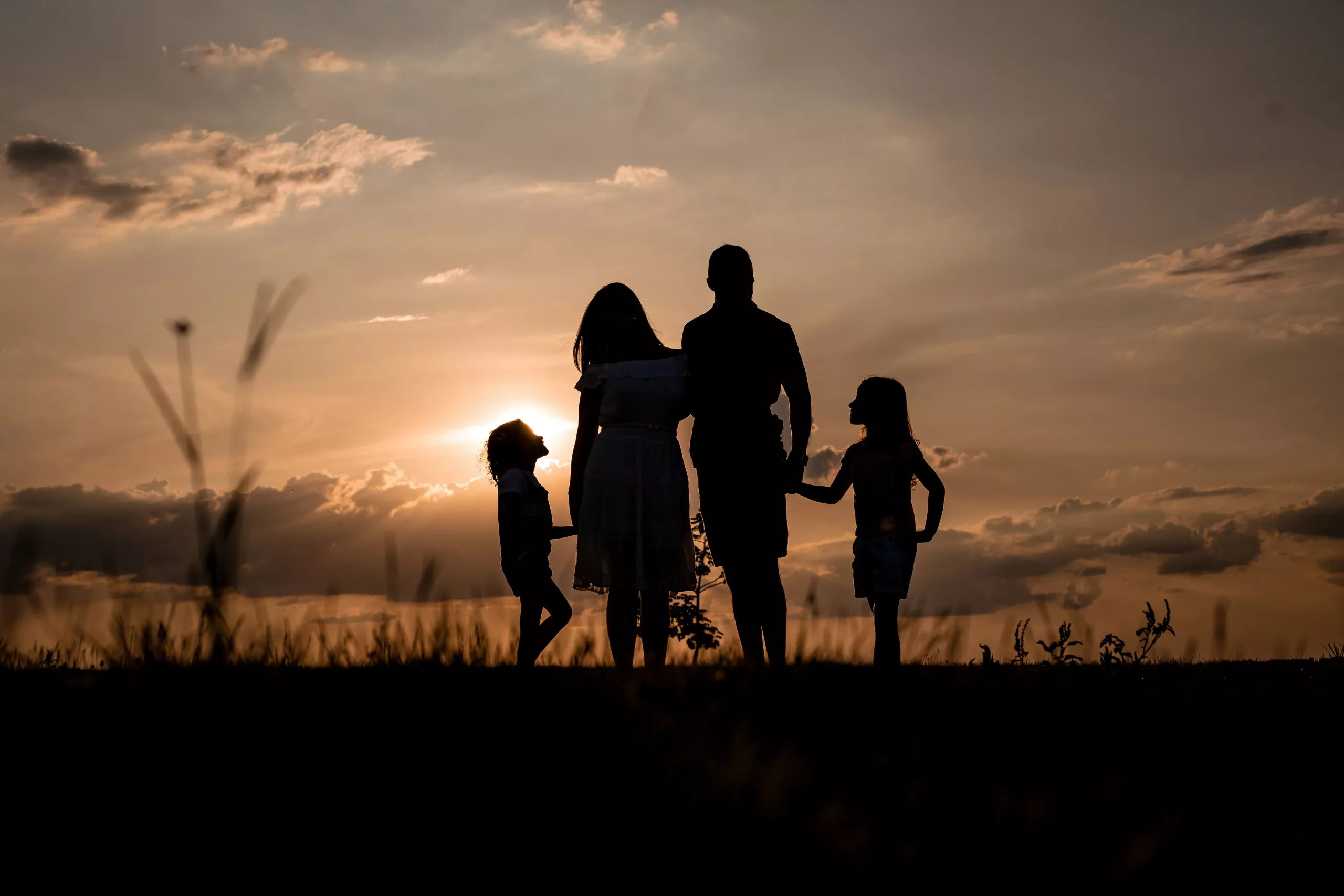 A family standing together in a field at sunset
