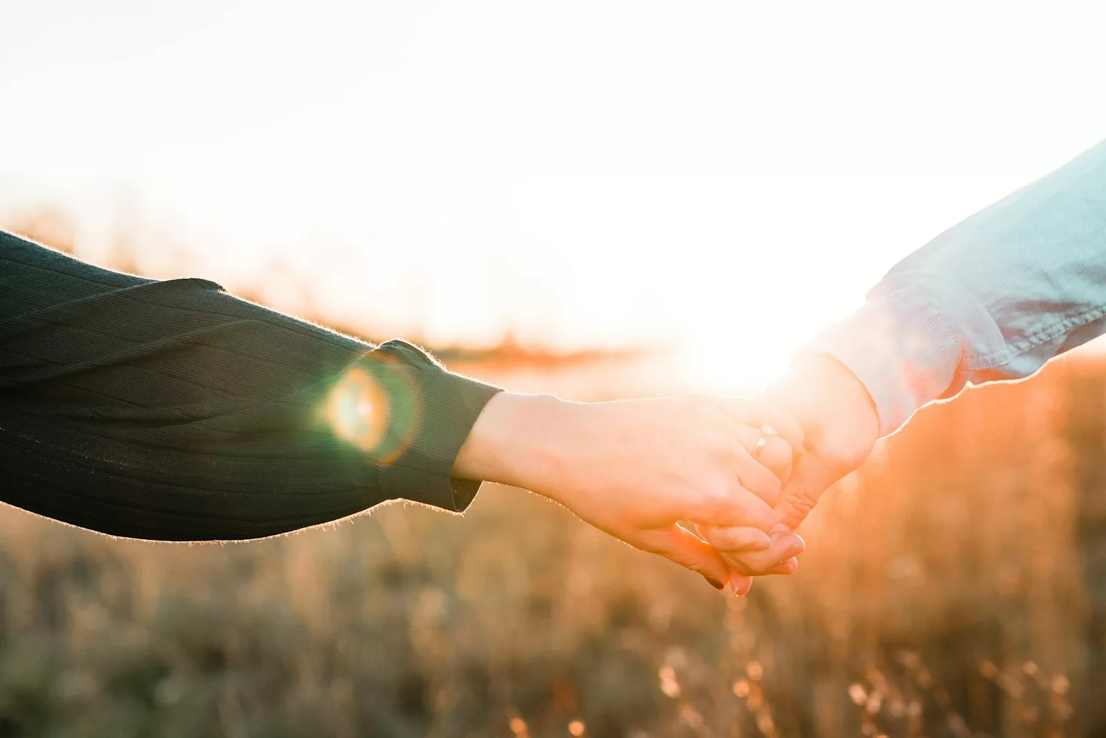 Two people holding hands in warm light